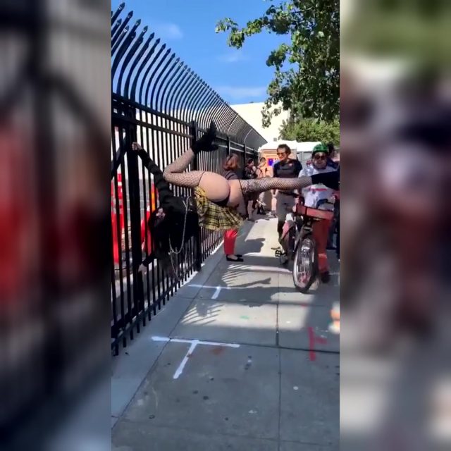Woman Flashes Her Butt While Hanging From a Street Fence